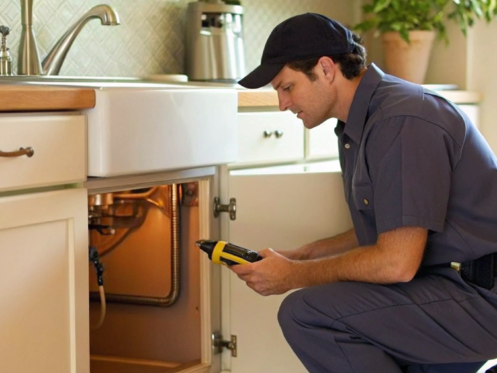A plumber uses a detection tool to fix a gas leak under a sink.